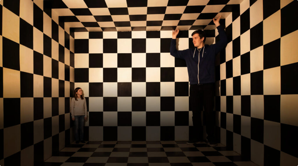 Pokój Amesa w muzeum iluzji Mielno – złudzenie perspektywiczne zmieniające postrzeganą wielkość ludzi